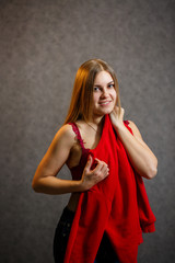 Fototapeta premium Girl tries on a red sweater on a gray background