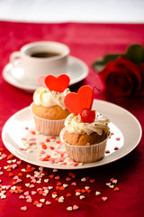 Valentine cupcakes decorated with sweet hearts on wooden table on a red background