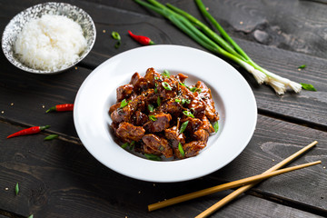 General Tso Chicken plate on dark background. General Tso's chicken (also tsao or tao) is a popular chinese restaurant food with deep-fried crispy chicken covered in a tasty sweet and spicy sauce.