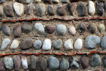 Natural stones and terracotta roof tiles rows on an old wall