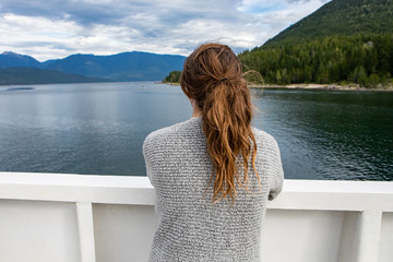 Close up shot from behind of a female passenger of a ferryboat navigating in a canadian lake....