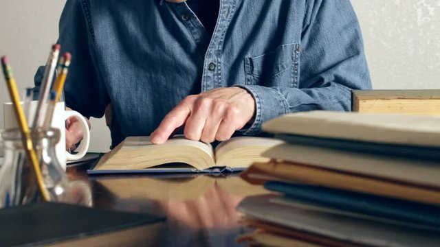 Man at desk taking notes from a book