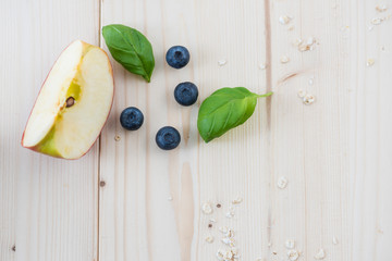 Morning breakfast with apple pieces and blueberries all on a light wooden table.