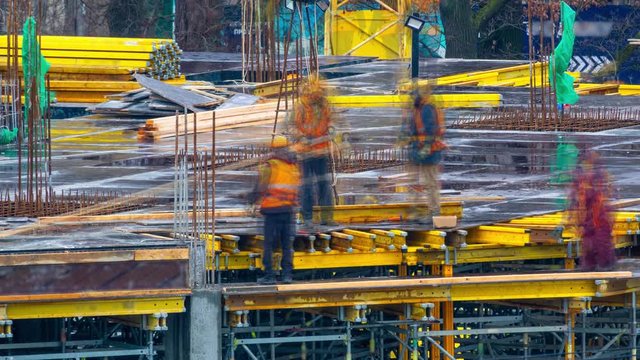 Group of construction workers at a construction site. Builders laying metal reinforcements for new floor slabs. Time lapse. Zoom effect