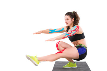 Amazing stronger sports fitness woman make exercises isolated over white wall background. Kinesio...