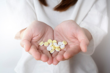 Hand of a woman holding a pill on white background.Healthcare and medical concept.