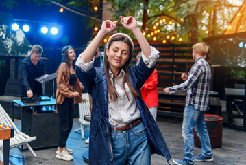 Brunette stylish girl dancing at birthday party with her friends.