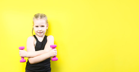 Theme sport and health. Beautiful caucasian child girl with pigtails posing on yellow background with smile. little athlete holding pink dumbbells. Banner for advertising, space for text copy space