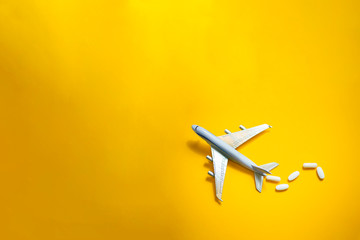 Plane figurine with pills spilled. Travel and medicine concept. Flat lay view with copy space on minimalist gray background. - obrazy, fototapety, plakaty