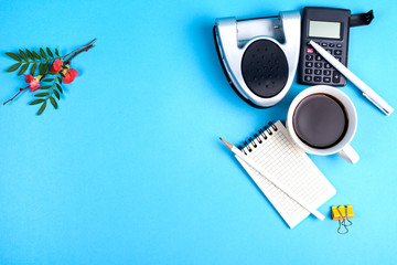 workspace top view. office Desk with office supplies, calculator, punch and coffe. top view blue background