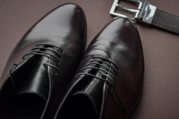 Close of fashionble men dark red leather shoes and belt on dark background. 