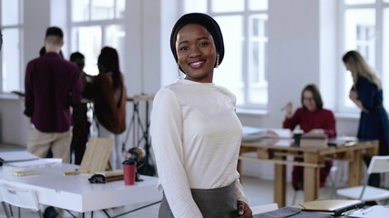Happy smiling young successful African entrepreneur business woman wearing turban smiling at modern...