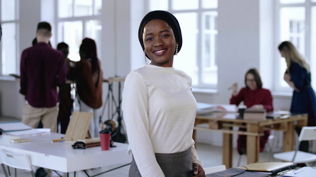Happy Smiling Young Successful African Entrepreneur Business Woman Wearing Turban Smiling At Modern Light Loft Office.