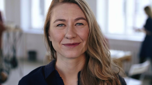 Close-up Portrait Of Happy Caucasian Blonde Business Woman Posing At Trendy Modern Office Workplace, Smiling Cheerfully.