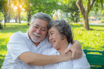 Romantic senior couple. Elderly man or Senior asian husband embracing senior wife. Lovely elderly couple talking about their life, smiley faces at park. Old man and old woman love each other so much