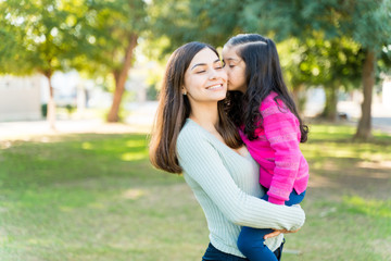 Adorable Girl Kissing Mother At Park