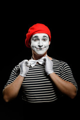 Man straightens a bow tie. Male mime got striped t-shirt and red hat