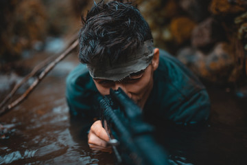 The hunter or soldier who got into the water is aiming with his gun.