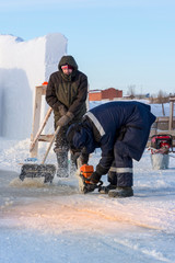 Fototapeta na wymiar Worker cuts the ice with a gasoline saw
