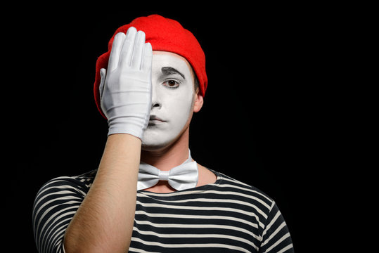 Mime covering half of face with hand