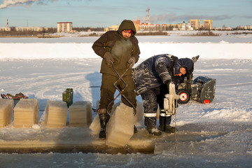 Worker cuts the ice with a gasoline saw