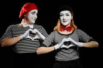 Mimes makes heart shapes with hands. Man and woman as mime artists