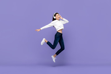 Asian woman jumping and listening to music on headphones