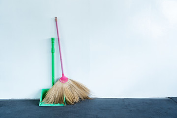 Bloom and dustpan put together on the white wall - obrazy, fototapety, plakaty