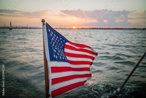American flag flies from transom of sailboat with sunset in background in Galveston Bay Texas