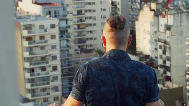 Handsome man with short colored hair on the terrace overlooking the city