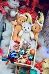 Many teddy bears are in a wooden box filled with Christmas decorations. The floor is covered with white cotton.. Selectve focus.