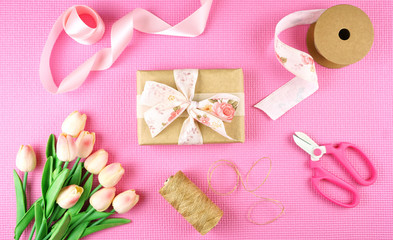 Fototapeta na wymiar Gifts wrapped in kraft paper and pink ribbons overhead flat lay for Mother's Day, birthday or Valentine's Day celebrations.
