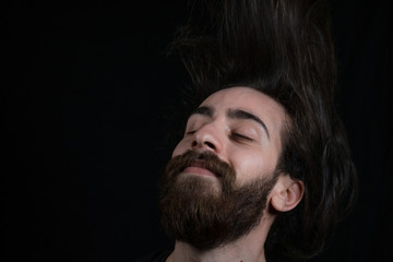 Fototapeta premium Hipster teenager man hair tossing, black isolated background.