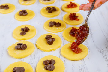 Filling jam into raw cookie dough circles.