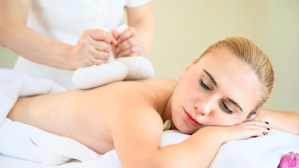Obraz na płótnie Canvas Health care and thai massage. Beautiful woman getting thai herbal ball compress back and shoulder massage in spa salon