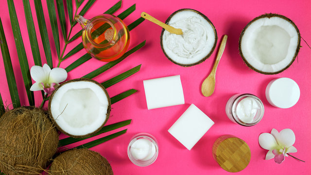 Coconut cosmetics theme flat lay creative layout overhead with pro environment alternative plastic free soaps, moisturizers and beauty products on modern pink background.
