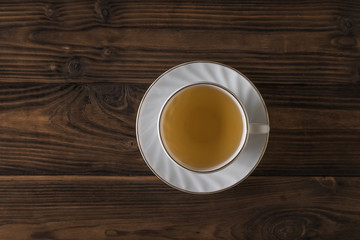 White Cup with green tea on a wooden table. Flat lay.