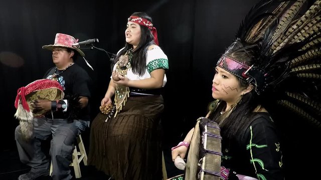 group of shaman Teotihuacanos, Xicalanca - Toltec in black background, with traditional dress dance with a trappings with feathers and drum