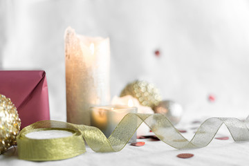 New year and Christmas card, colorful gold and silver baubles with a gift box, ribbon, candles and confetti on a white background. selective focus.