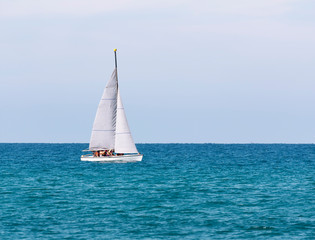 Fototapeta premium A sailboat with a crew in life jackets is floating in the sea