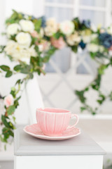 Elegant vintage cup on background of terrace overgrown with flowers. Spring pretty background. Spring and Easter mood. Shabby chic style. Morning tea ceremony. Tender beautiful decor