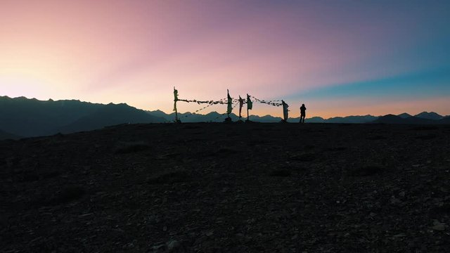 Beautiful silhouette of a person clicking pictures during sunset in spiti valley , himachal pradesh | prayer flags