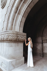 Beautiful stylish blonde bride posing near old castle wall wedding concept
