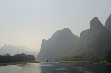 Cruise ship on the hazy Li River in China among the karst limestone peaks of Guangxi