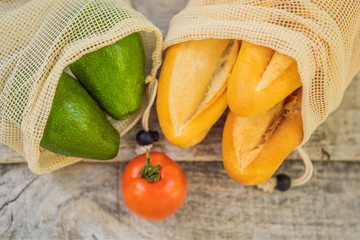 Fresh bread, avocado and tomatoes in a reusable bag on a stylish wooden kitchen surface. Zero waste concept