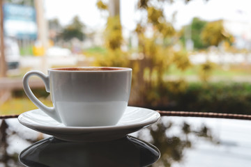 white cup of hot coffee drink put on glass table in cafe