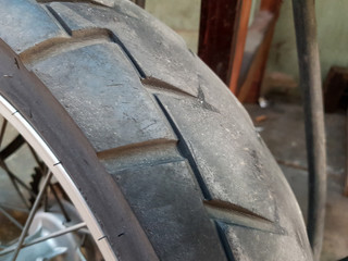 Close up old rear wheel motorcycle rubber tire after used for long distance, safety and maintanence concept.