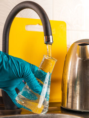 water purification specialist tap water pours into a glass flask.