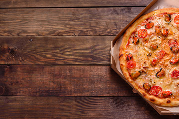 Tasty sliced pizza with seafood and tomato on a concrete background