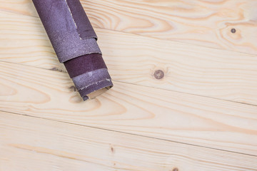 sandpaper twisted into a roll lies on a wooden board. Close-up. There is a tint.